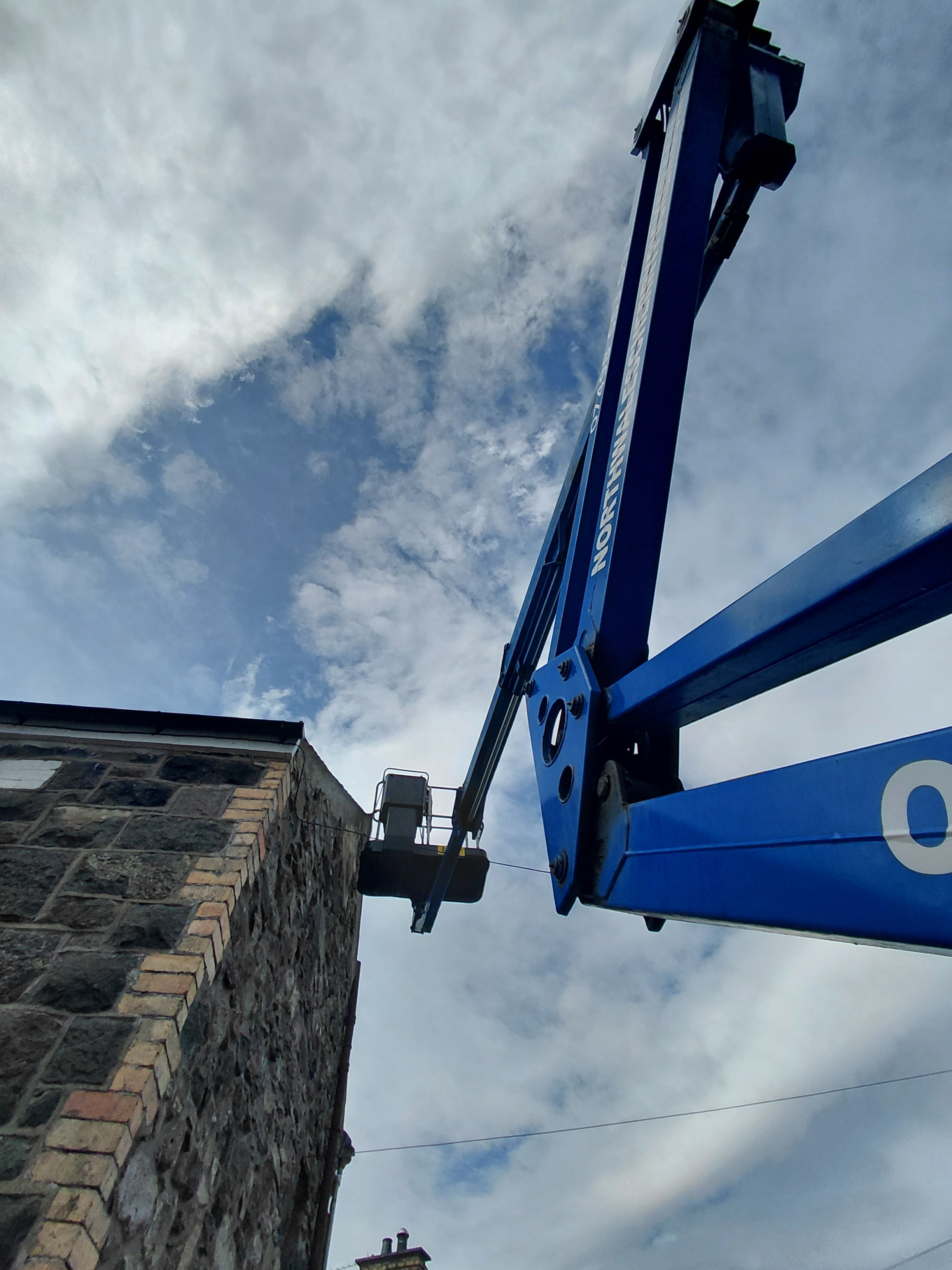 Cherry picker arm reaching chimney on stone building
