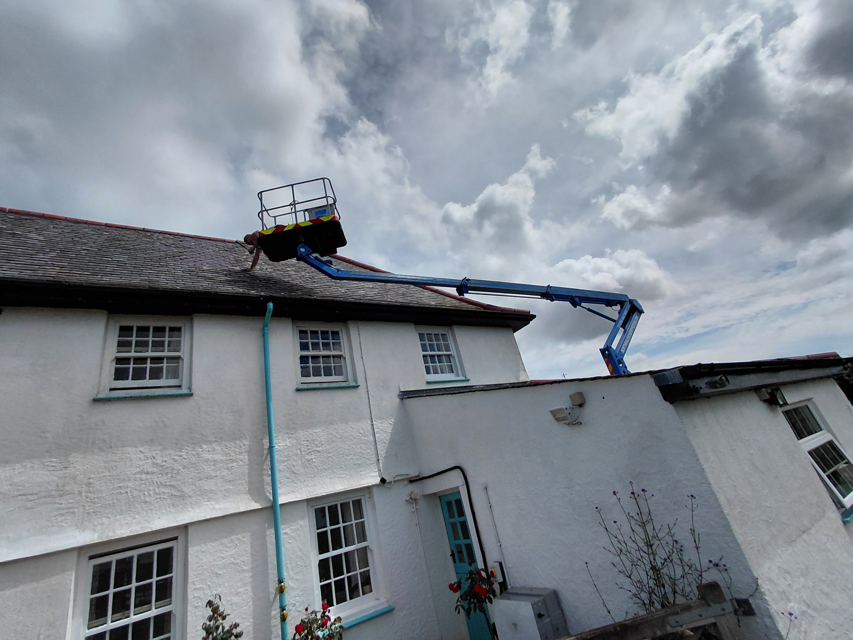 Cherry picker basket at roofline of white North Wales property